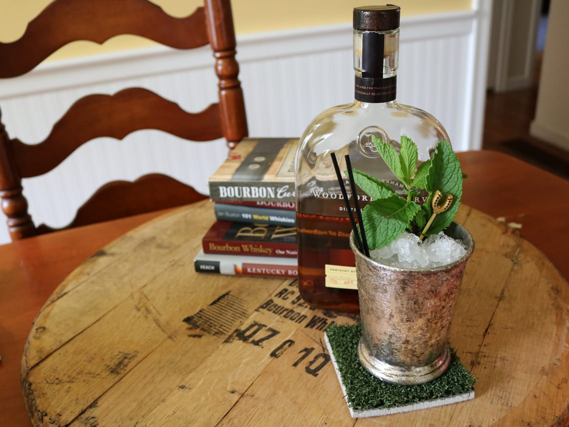 Mint Julep on an astroturf coaster in front of a bottle of bourbon and a pile of bourbon books.